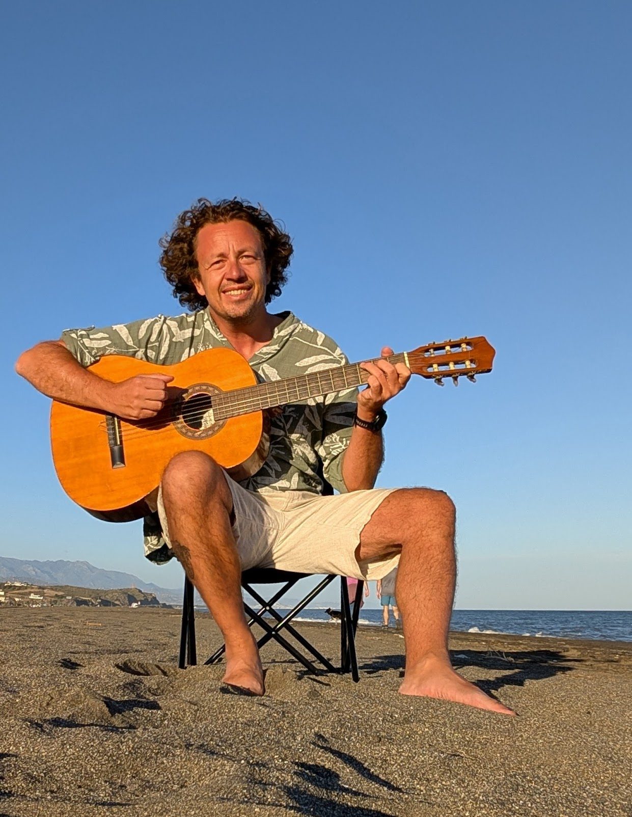 Ken playing guitar on the beach in Malaga